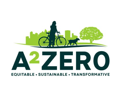 A2Zero logo in light and dark green with a dog and a bicyclist and dog in a city and a tree with a solid white background