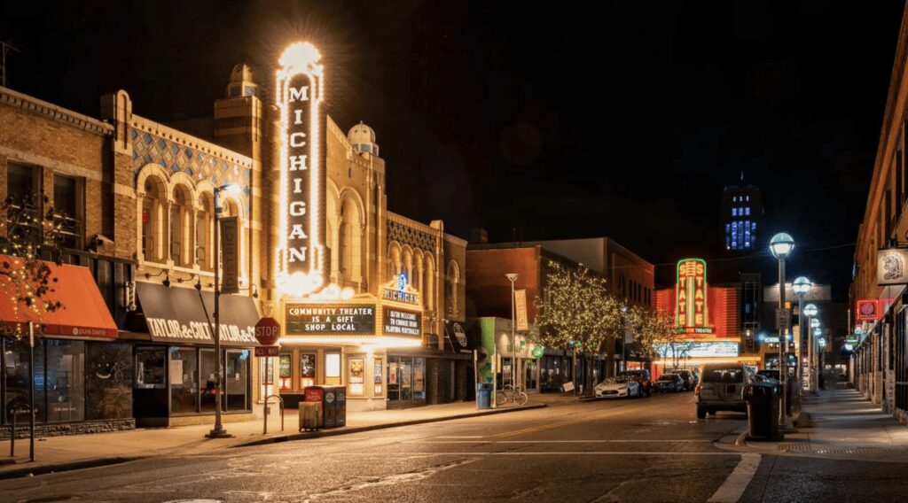 Night outdoor photo of the Michigan and State Theaters, long shot off Liberty St with the marquees lit and full buildings in view